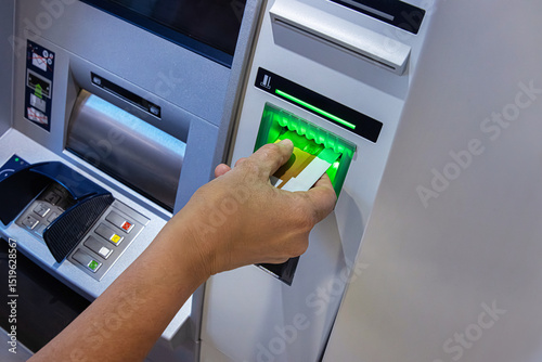 Closeup of a person hand inserting a bank card into an ATM machine slot  for money withdrawal
