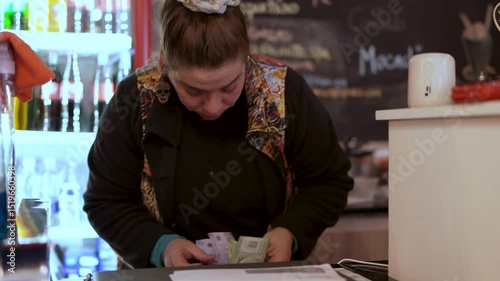 Coffee shop employee counting money at the counter