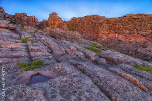 plateau with lake or puddle on top of mountain among layered rocks under setting sun. Layered rocks. Beautiful summer landscape at sunset