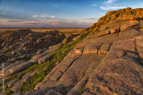 on top of a mountain overlooking the steppe under the sunset sky. Layered rocks. Beautiful summer landscape at sunset