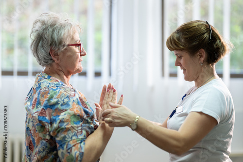 Senior Physical Therapy Session.Senior woman doing physical exercises with the help of a smiling therapist. Concept of elderly rehabilitation and movement recovery.