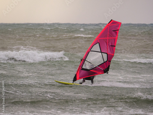 Water Sport Activity - Windsurfer Riding a Wave in Rough Sea on a Windy Day
