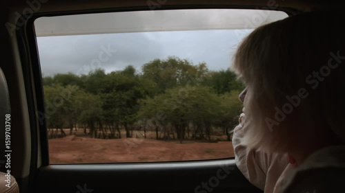 Young beautiful blonde woman traveling by car and enjoying view of landscape from window. Slow motion. Traveling gives feeling of freedom and joy