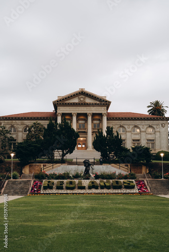 The exterior of the University of Redlands, with a green alley on the way to it and bushes in the shape of the university's name planted in front of it.