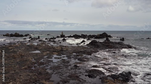 A moody seascape on La Graciosa, Lanzarote, featuring rugged black rocks and the ocean under an overcast sky.