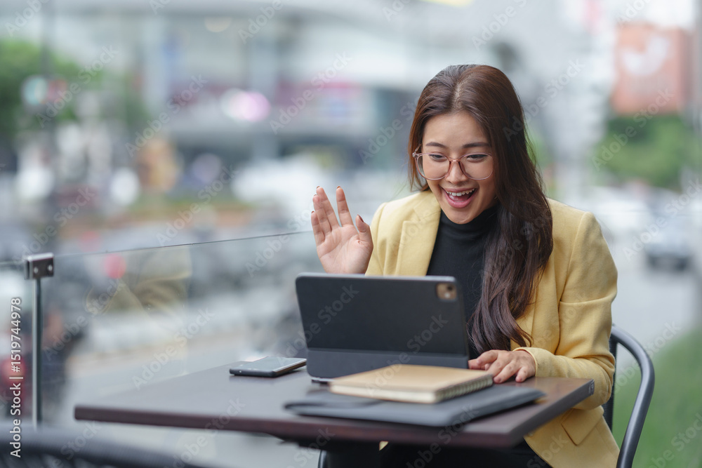 Young Asian businesswoman greeting during video conference on tablet, working remotely in outdoor cafe Young Asian businesswoman greeting during video conference on tablet, working remotely in outdoor cafe
