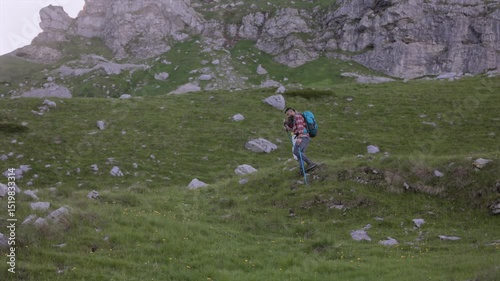 Young hikers traversing verdant mountain meadow with trekking equipment, sharing intimate moment while breathing deeply and savoring panoramic landscape during scenic outdoor adventure