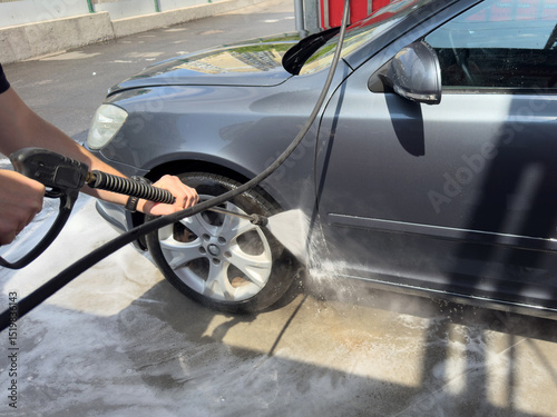 Closeup of male driver washing his car with contactless high pressure water jet