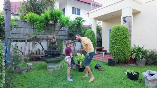 Father and daughter carrying potted plants in home garden