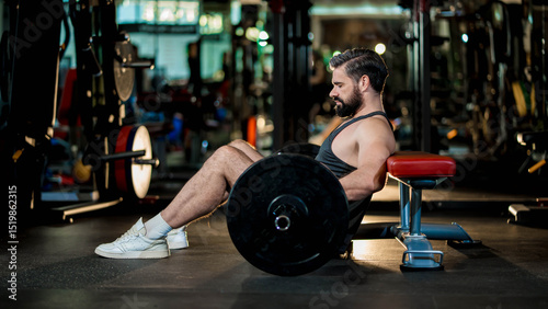 Fotografie Strong man in black tank top preparing for hip thrust exercise with barbell on b