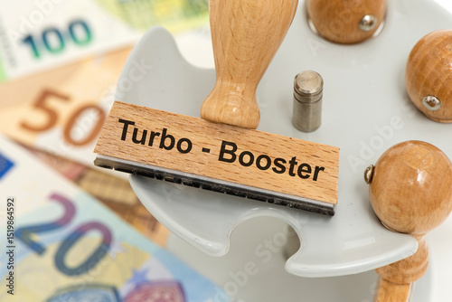 Ein Holzstempel liegt auf einem Stempelhalter über Euro Banknoten als Symbol für den Turbo-Booster der Bundesregierung