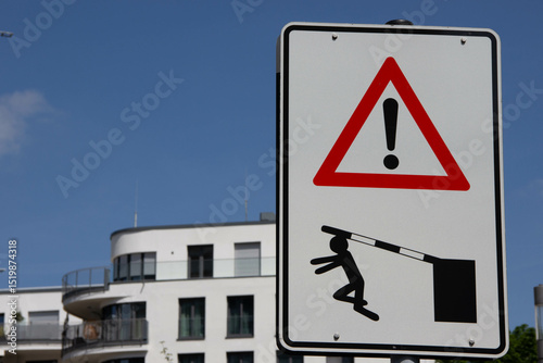 Warning sign with exclamation mark and icon of person being hit by a barrier arm, symbolizing safety hazard and caution in restricted areas.