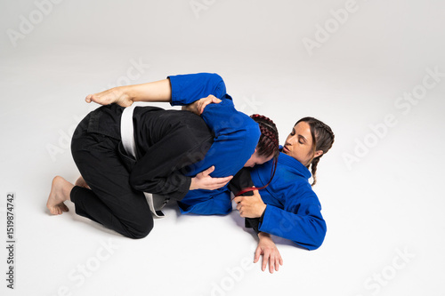 Two female athletes performing jiu jitsu techniques on white background