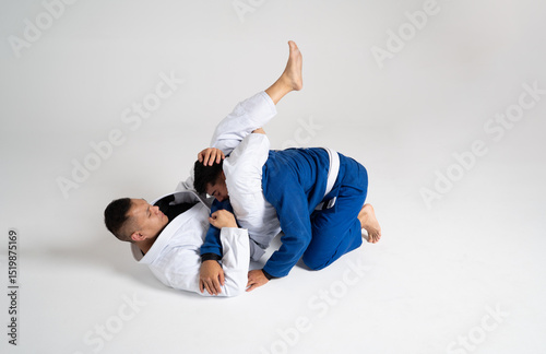Two jiu jitsu athletes grappling on white background