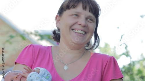 woman smiles with baby, mother holds baby in arms and laughs in yard