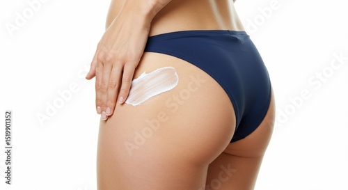 Woman applies skincare cream to buttock, against a white backdrop. For beauty ads