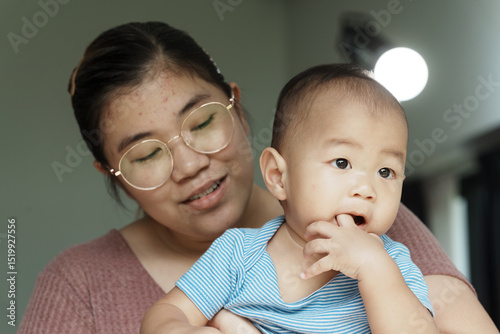 At home, a baby plays with their parents and aunt, sharing moments of laughter and occasional tears. The lively atmosphere reflects the warmth, joy, and emotional ups and downs of family life.
