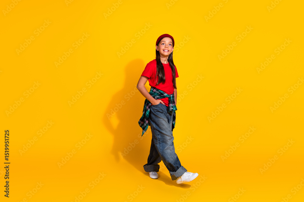 Fototapeta premium Happy young girl dressed casually with a red t-shirt and beanie smiling against a bright yellow background