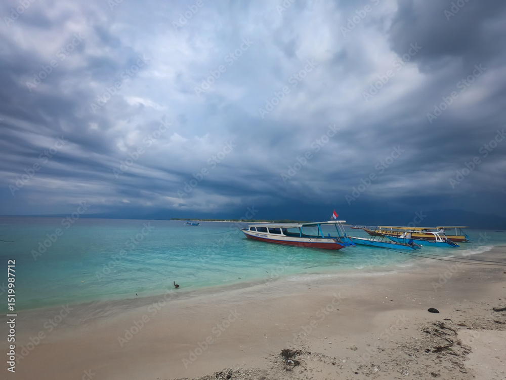 Fototapeta premium Beautiful seascape with touristic boats on sandy beach at Gili Meno island, Bali, Indonesia.&nbsp; Storm clouds, turquoise sea water. 