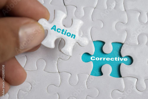 Hand holding piece of jigsaw puzzle with word Corrective action. Business and finance concept