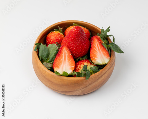Group of strawberries in a wooden bowl on a white background
