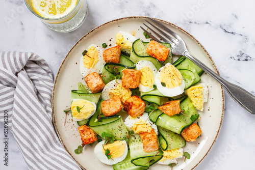 Delicious salmon and egg salad served on a plate with fresh cucumber and herbs for a healthy meal at lunchtime