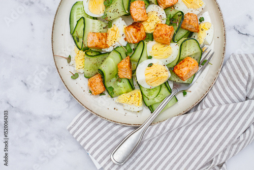 Delicious salmon and egg salad served on a plate with fresh cucumber and herbs for a healthy meal at lunchtime