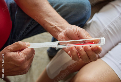 Senior man opens anticoagulant syringe for his wife after surgery. Home medical care following hospital discharge. Postoperative support and treatment in domestic recovery settings.