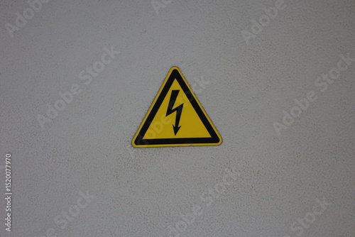 High voltage lightning triangle safety sign on electrical cabinet door, black yellow electrical energy warning label isolated image