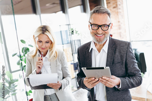Professional team of mature businesspeople in an office collaborating with technology and documents, showcasing teamwork and dedication photo