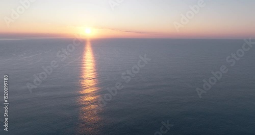 Aerial view of sunrise over the sea, with sunlight reflecting beautifully off the ocean surface.