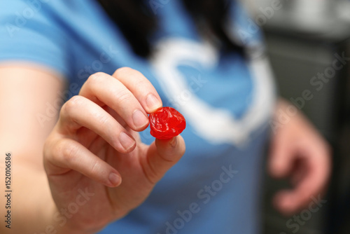Woman's hand holding a vibrant red dried cherry berry, showcasing natural sweetness and healthy snacking