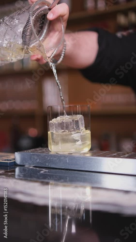 The bartender pours the finished cocktail into a glass