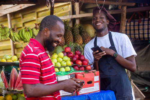 Canvas Print young african man selling tomatoes in a local african market collecting money fr