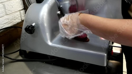 A woman's hand lays out sliced ​​delicious sausage on a slicer close-up