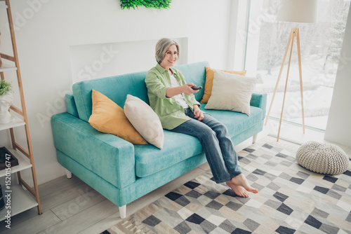 Elderly woman enjoying leisure time at home on a comfortable sofa in a modern living room with cozy decor