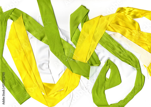 Green and yellow satin ribbons entangled on a white background. Vivid colors and smooth texture for design purposes.