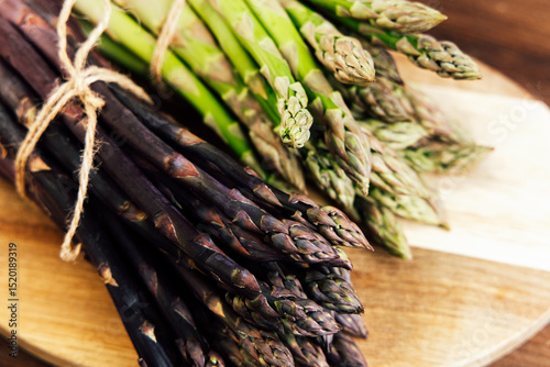 Freshly harvested asparagus varieties on a wooden cutting board in a rustic kitchen
