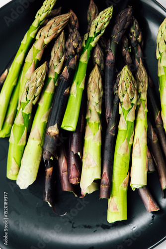 Fresh asparagus arranged beautifully on a black plate for a vibrant culinary presentation