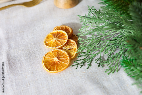 Dried orange slices arranged on a linen tablecloth with green foliage nearby