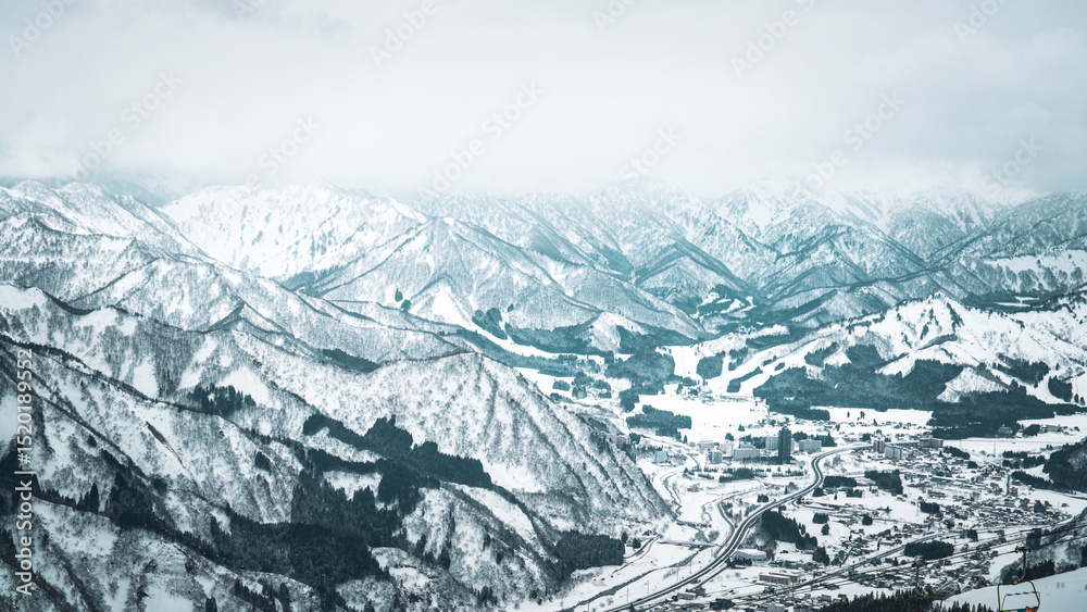 Obraz premium A breathtaking panoramic view of snow-covered mountain ranges including Ishiuchi Maruyama, Yuzawa Kogen, and distant peaks near Echigo-Yuzawa in Niigata, Japan, captured from Gala Yuzawa station.