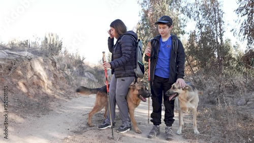 Hikers petting their german shepherd dogs while walking on a trail