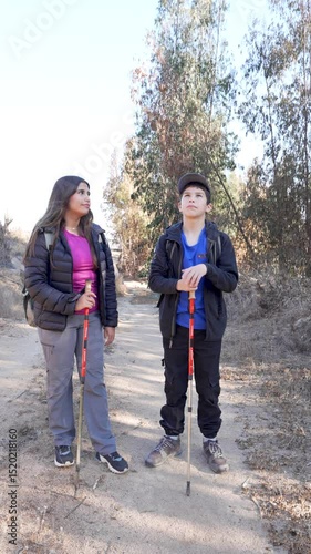 Two young hispanic hikers admire the landscape during a mountain trek