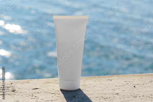 Mockup of a white cosmetic tube on natural stones on the sea background. Ideal for skincare, sunscreen, or organic cosmetic branding in a summer beach concept.