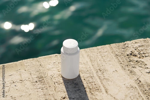 White mockup supplement jar on rocky stone by the sea. Natural treatment idea, alternative medicine, pharmaceutical, health and wellness care, purity and therapy concept.