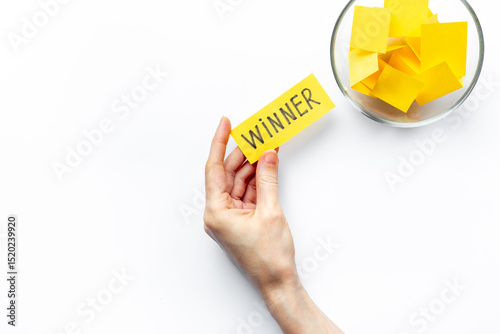 Hand is holding raffle ticket winner near glass jar, top view. Luck and lottery concept