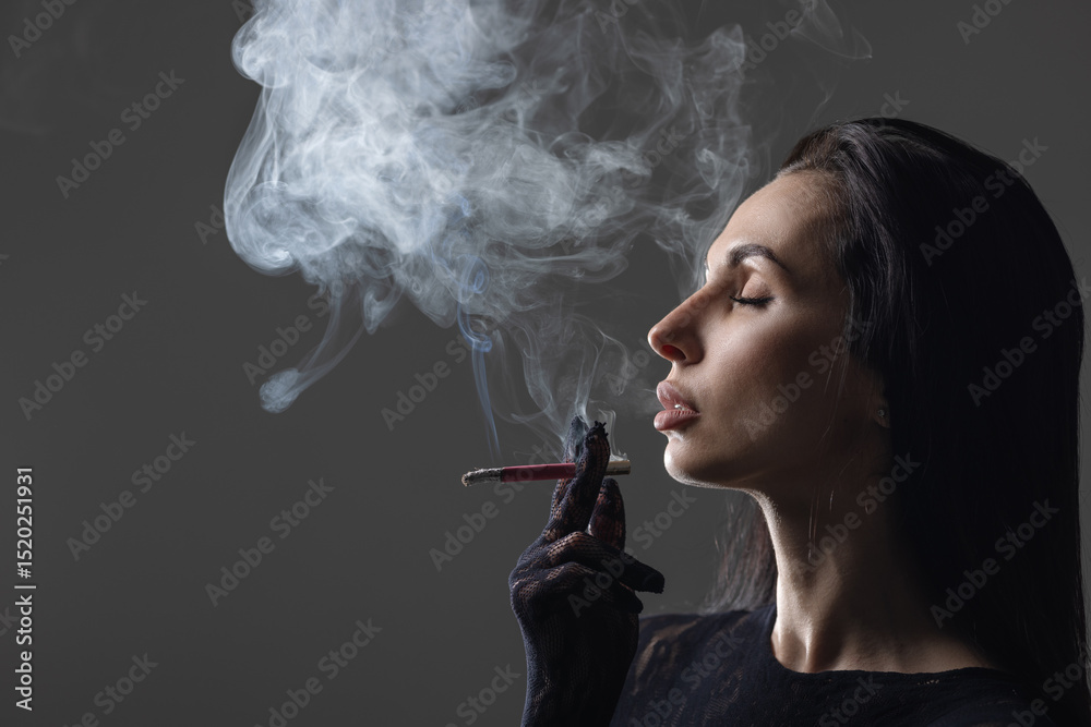 Obraz premium Elegant woman in black gloves smoking a cigarette with eyes closed, surrounded by dense smoke, isolated against a dark background. Concept of addiction, mystery, and sensuality.