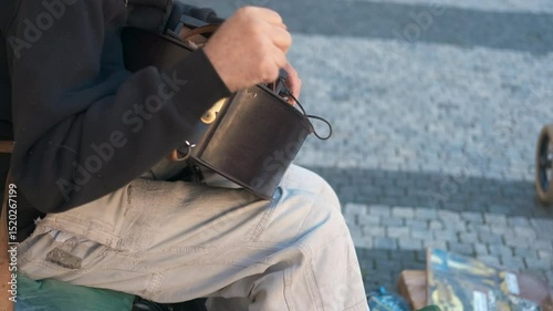 Street musician playing hurdy-gurdy in urban setting. Seasoned street musician performing traditional hurdy-gurdy, generating melodic sounds while sitting in urban environment
