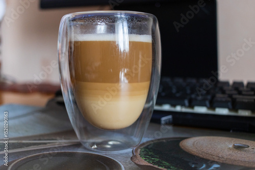 Layered Latte Macchiato in a Double-Walled Glass on a Desk