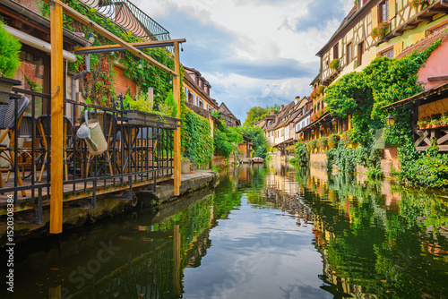 Fototapeta Naklejka Na Ścianę i Meble -  Water level view from a boat as it passes by half timbered colorful historic buildings along the Lauch Canal in the historic Petite Venise district of Colmar, France.